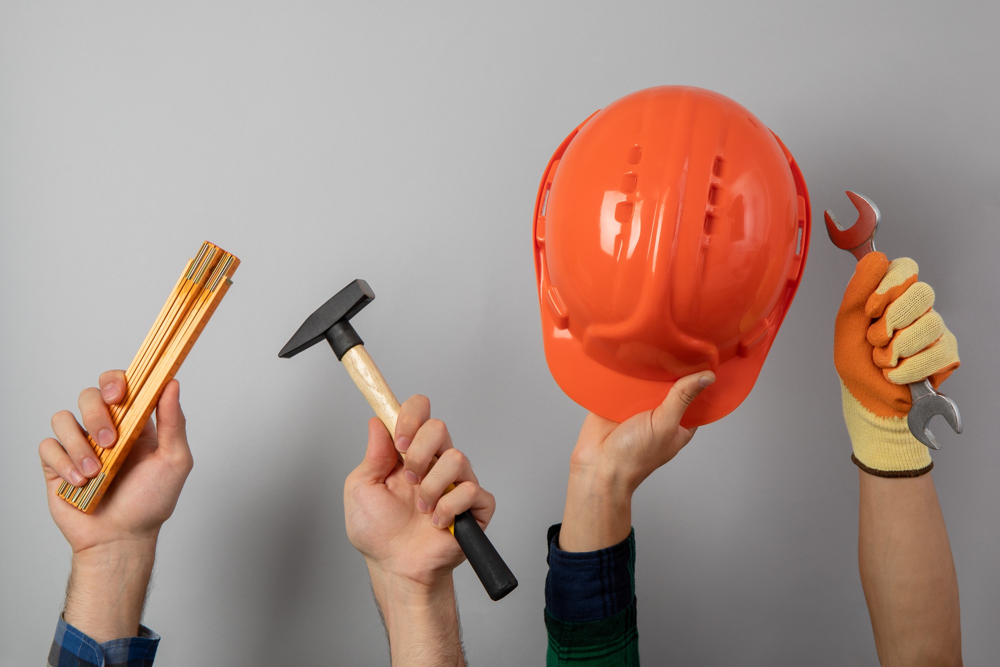 Hands with different construction tools on gray background